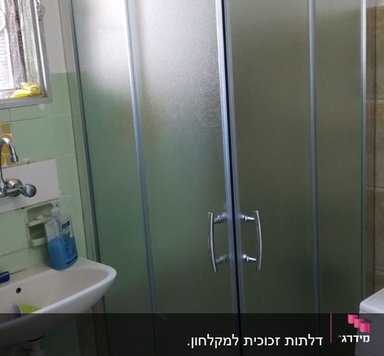 מקלחון זכוכית עם דלתות מתכת בחדר אמבטיה